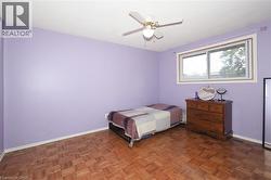 Bright room featuring parquet wood-finish flooring, a ceiling fan with integrated lighting, and a large window with white trim -