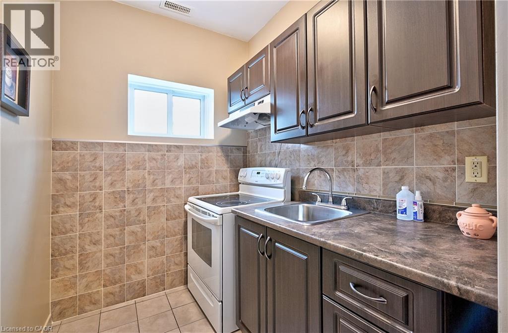 Kitchen area featuring dark wood-finish cabinetry, a stainless steel sink with a chrome faucet, and a stone-look countertop - 1476 Barton Street E, Hamilton, ON - Indoor Photo Showing Kitchen
