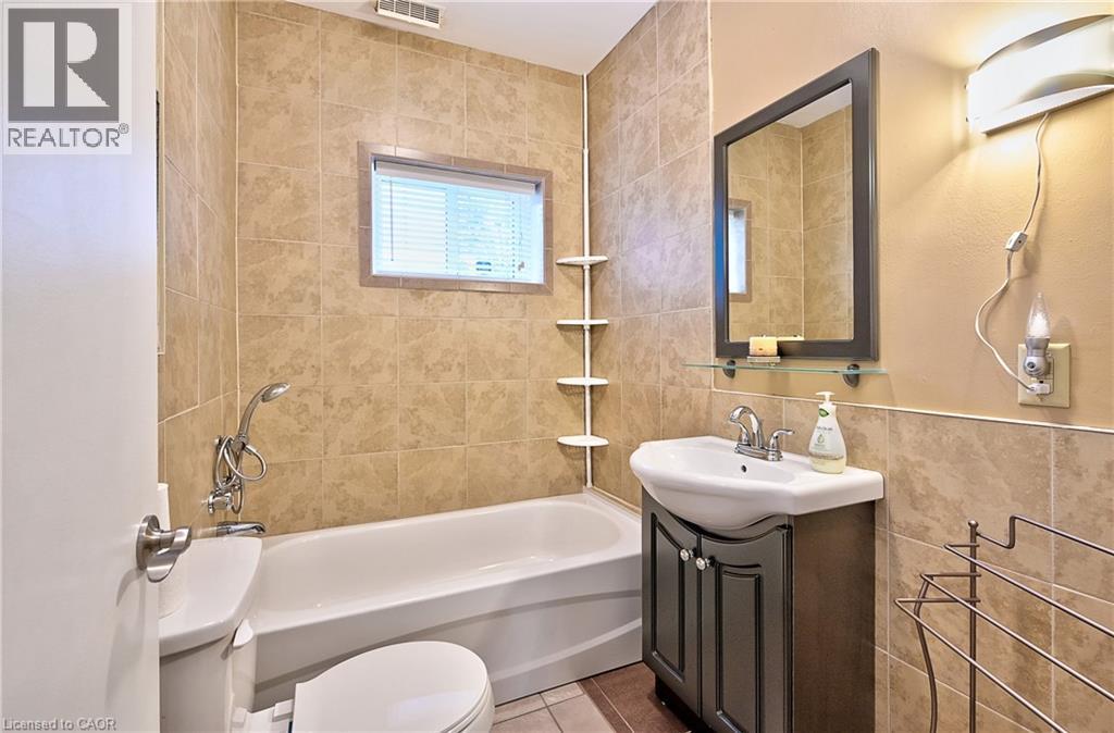 Bathroom featuring a tiled shower surround, integrated bathtub, and a vanity with a drop-in sink - 1476 Barton Street E, Hamilton, ON - Indoor Photo Showing Bathroom