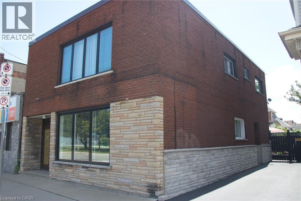 Brick exterior featuring stacked stone accents, multiple large windows, and a dedicated paved side area - 1476 Barton Street E, Hamilton, ON - Outdoor With Exterior
