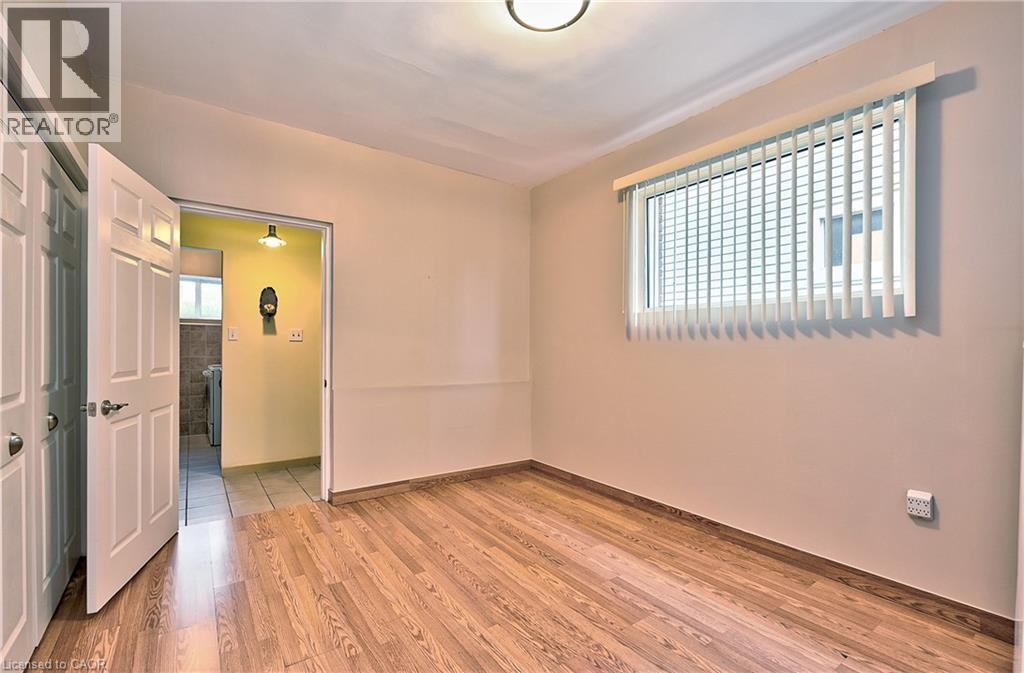Room featuring wood-finish flooring, a window with vertical blinds, and a flush-mount ceiling light - 1476 Barton Street E, Hamilton, ON - Indoor Photo Showing Other Room