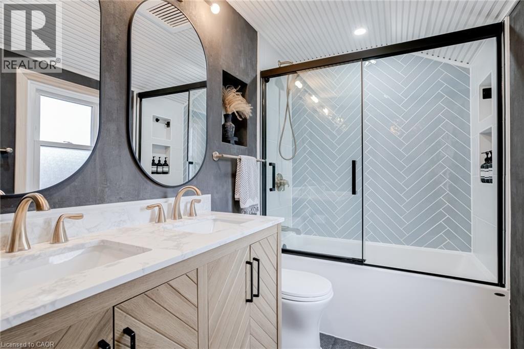 Full bath featuring double vanity and bath / shower combo with glass door - 624 Burgess Avenue, Hamilton, ON - Indoor Photo Showing Bathroom