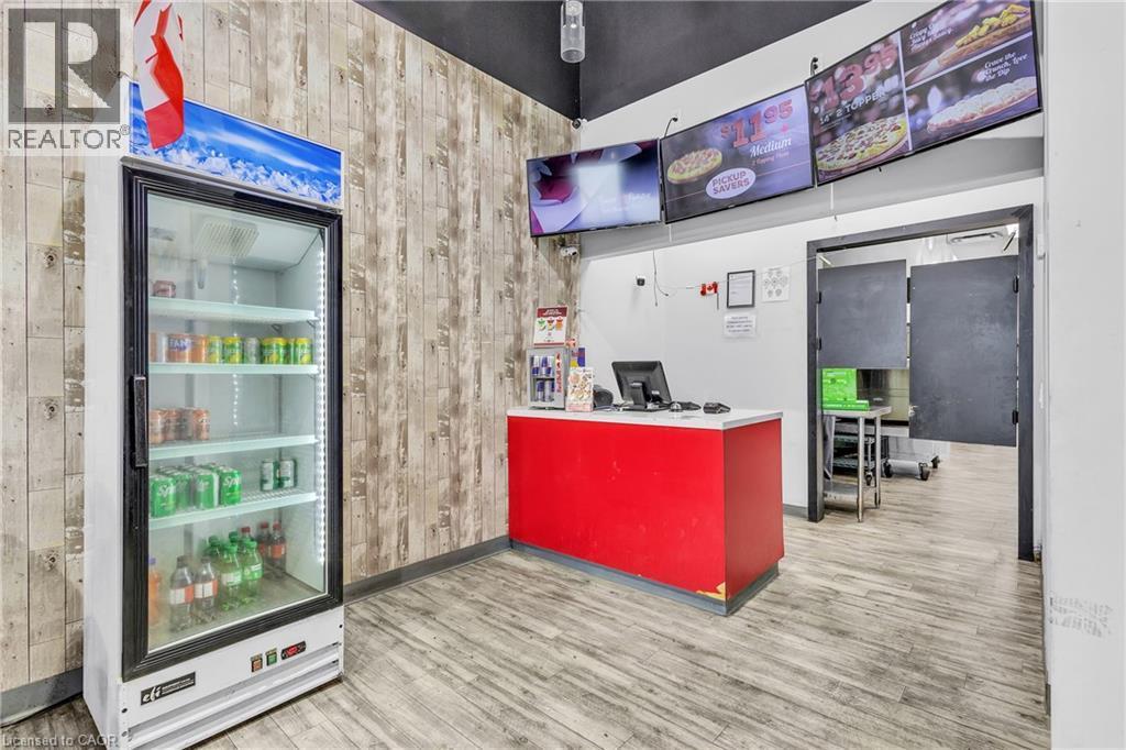 Retail counter area featuring wood-finish flooring, accent wall paneling, and a red service counter - 545 Hespeler Road, Cambridge, ON