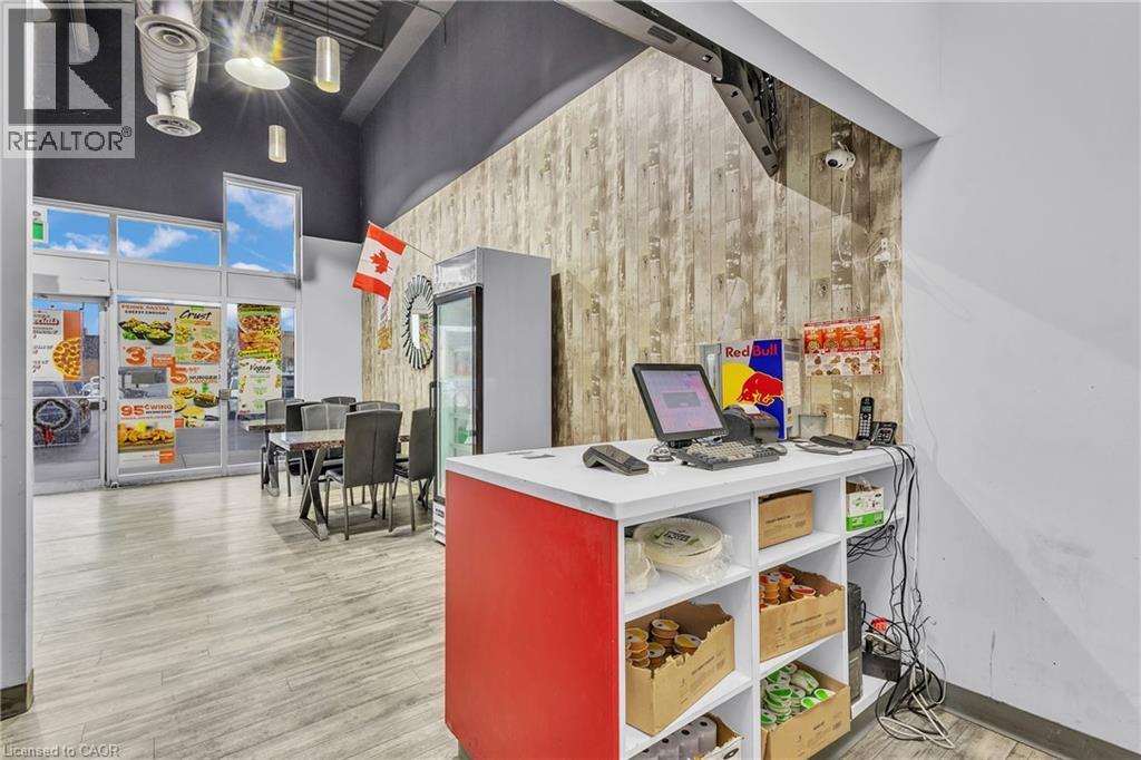 Retail space featuring wood-finish flooring, a wood-panel accent wall, and a high ceiling - 545 Hespeler Road, Cambridge, ON
