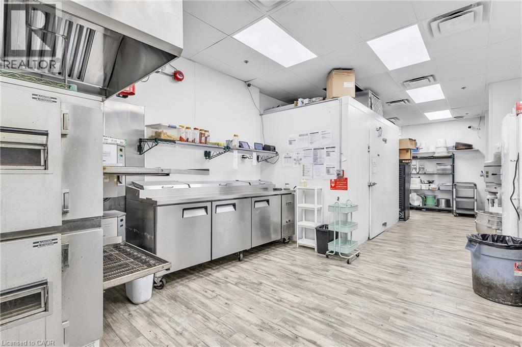 Commercial kitchen space featuring a stainless steel exhaust hood, built-in stainless steel refrigeration units, and extensive stainless steel countertops - 545 Hespeler Road, Cambridge, ON