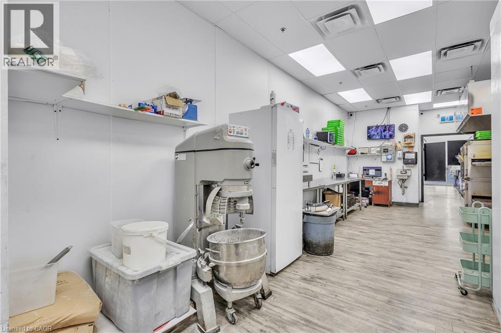 Commercial kitchen space featuring light wood-finish flooring, white panel walls, and a dropped ceiling with recessed lighting - 545 Hespeler Road, Cambridge, ON