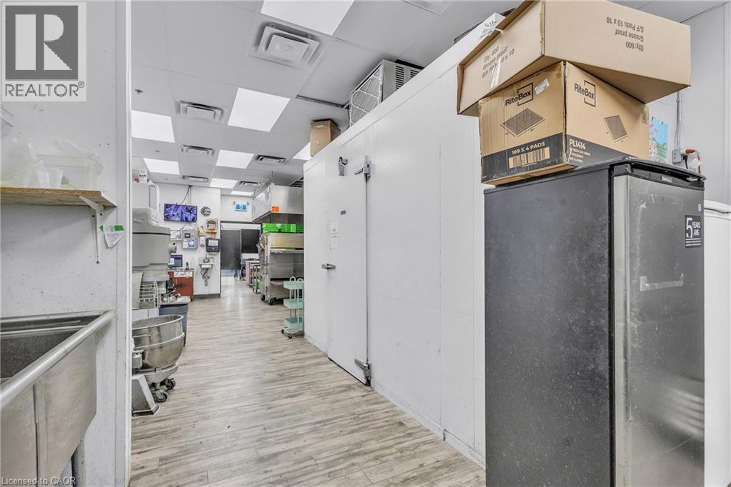 Spacious commercial kitchen area featuring light wood-finish flooring and a white drop ceiling with square lighting panels - 545 Hespeler Road, Cambridge, ON