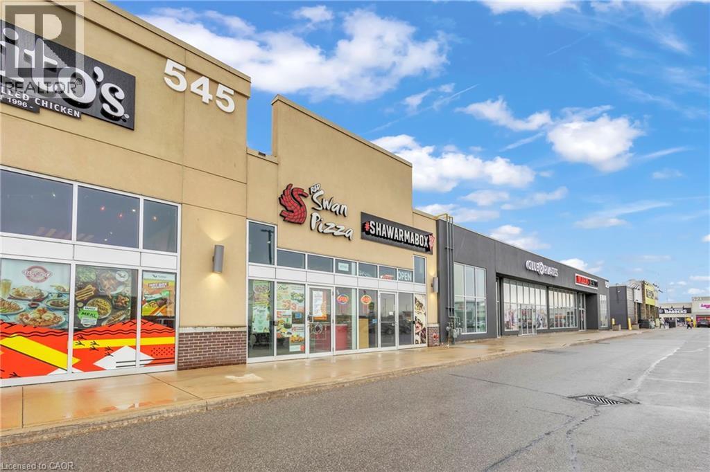 Commercial plaza exterior featuring a tan facade with large storefront windows and prominent signage - 545 Hespeler Road, Cambridge, ON