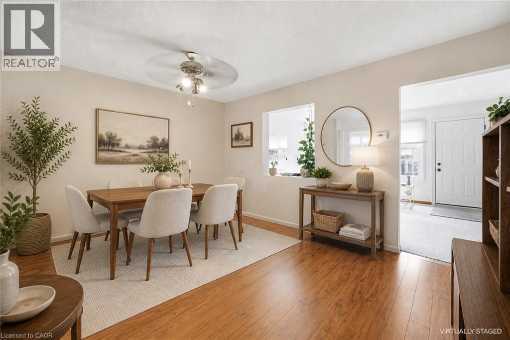 Dining area featuring wood-finish flooring, a ceiling fan with integrated lighting, and a pass-through window to an additional space - 299 Limeridge Ridge W Unit# 21, Hamilton, ON - Indoor Photo Showing Dining Room
