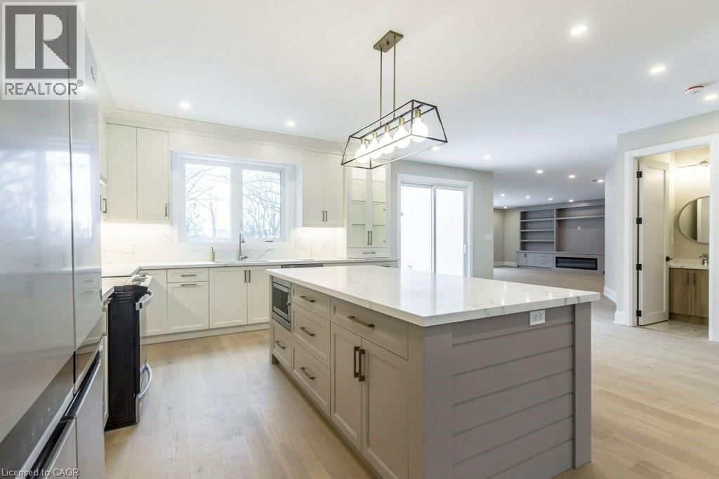 Kitchen with stainless steel appliances, a kitchen island, light wood-type flooring, and backsplash - 1105 Main Street E, Cambridge, ON - Indoor Photo Showing Kitchen With Upgraded Kitchen