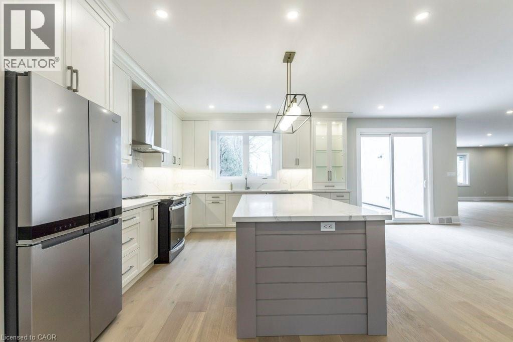Dual tone kitchen featuring stainless steel appliances, backsplash, a center island, light wood-style flooring, and two tone cabinetry - 1105 Main Street E, Cambridge, ON - Indoor Photo Showing Kitchen With Stainless Steel Kitchen With Upgraded Kitchen