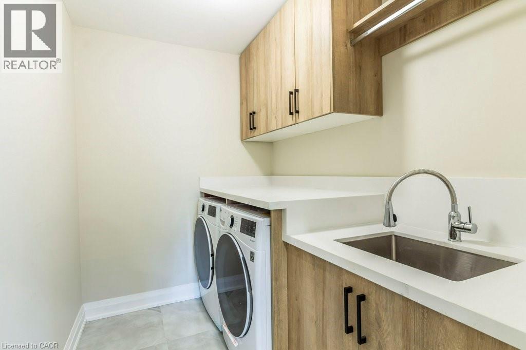 Laundry room featuring cabinet space, separate washer and dryer, and light tile patterned floors - 1105 Main Street E, Cambridge, ON - Indoor Photo Showing Laundry Room