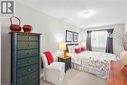 Carpeted bedroom featuring a window with drapes, a ceiling-mounted light fixture, and light-toned walls -