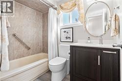 Full bathroom featuring a dark wood-finish vanity with a white countertop, oval mirror, and a window for natural light -