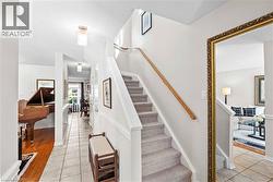 Entryway with a carpeted staircase and wood handrail -