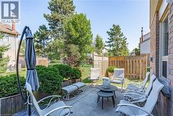 Concrete patio area featuring a brick exterior wall, a wood fence, and mature landscaping -