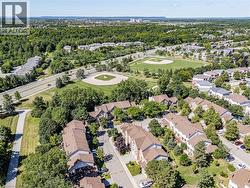 Aerial perspective showcasing extensive tree canopy, residential properties with varied rooflines, and a nearby sports field -