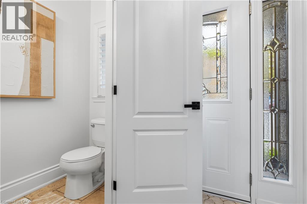 Entryway featuring a white paneled door with matte black hardware, sidelight with leaded glass, and stone tile flooring - 199 Hunter Street W, Hamilton, ON - Indoor Photo Showing Bathroom