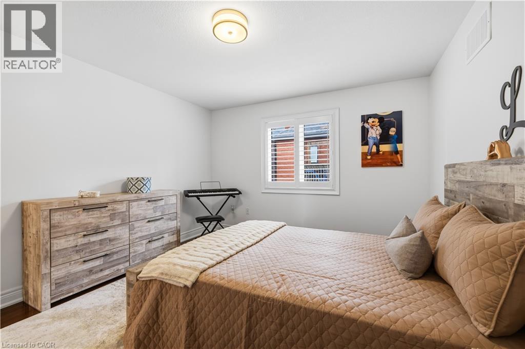 Bedroom featuring a window with white louvered shutters, a wood-finish bed frame, and a complementary wood-finish dresser with dark hardware - 199 Hunter Street W, Hamilton, ON - Indoor Photo Showing Bedroom