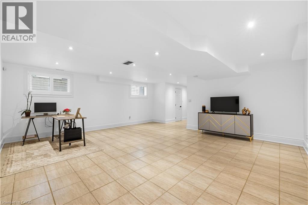 Spacious room featuring light-toned square floor tiling, multiple recessed ceiling lights, and white baseboards - 199 Hunter Street W, Hamilton, ON - Indoor