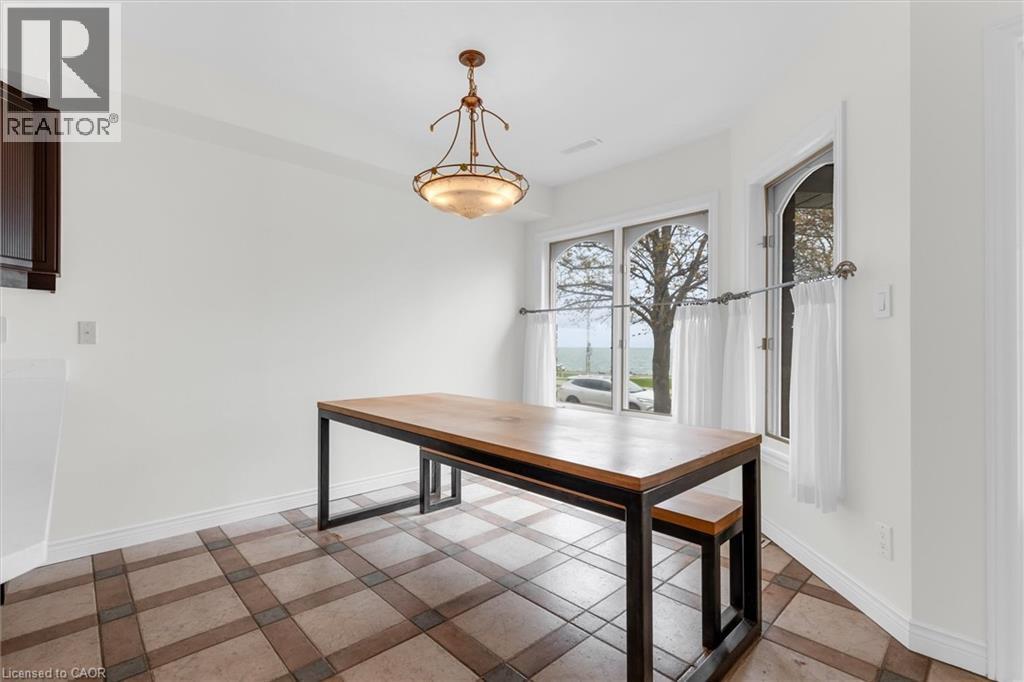 Dining area featuring patterned tile flooring, a large window overlooking a body of water, and an arched window - 1389 Lakeshore Road, Burlington, ON - Indoor