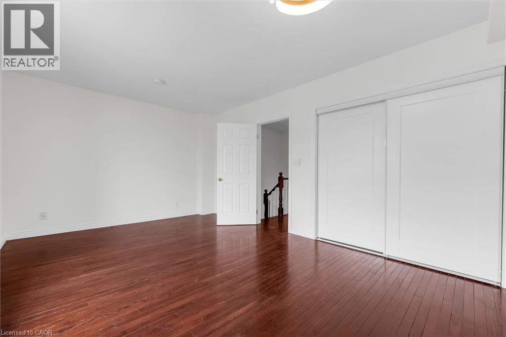 Spacious room featuring rich wood-finish flooring, white walls, and a contemporary ceiling light fixture - 1389 Lakeshore Road, Burlington, ON - Indoor Photo Showing Other Room
