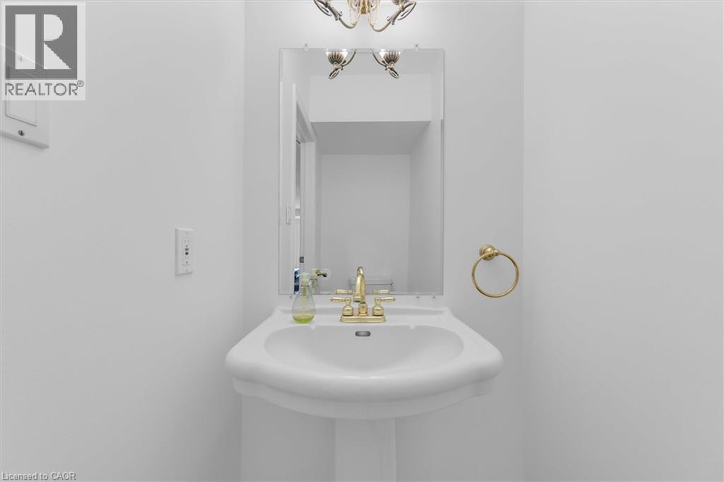 Pedestal sink with brass-finish faucet, framed mirror, and brass-finish towel ring - 1389 Lakeshore Road, Burlington, ON - Indoor Photo Showing Bathroom