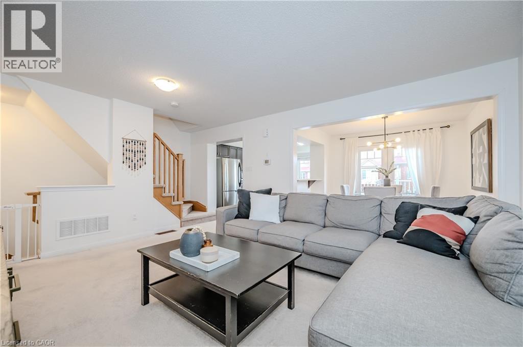Bright living area featuring light-toned carpeting and white walls - 525 Cavanagh Lane, Milton, ON - Indoor Photo Showing Living Room