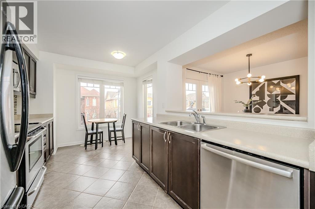 Bright kitchen with a pass-through opening to the dining area - 525 Cavanagh Lane, Milton, ON - Indoor Photo Showing Kitchen With Double Sink