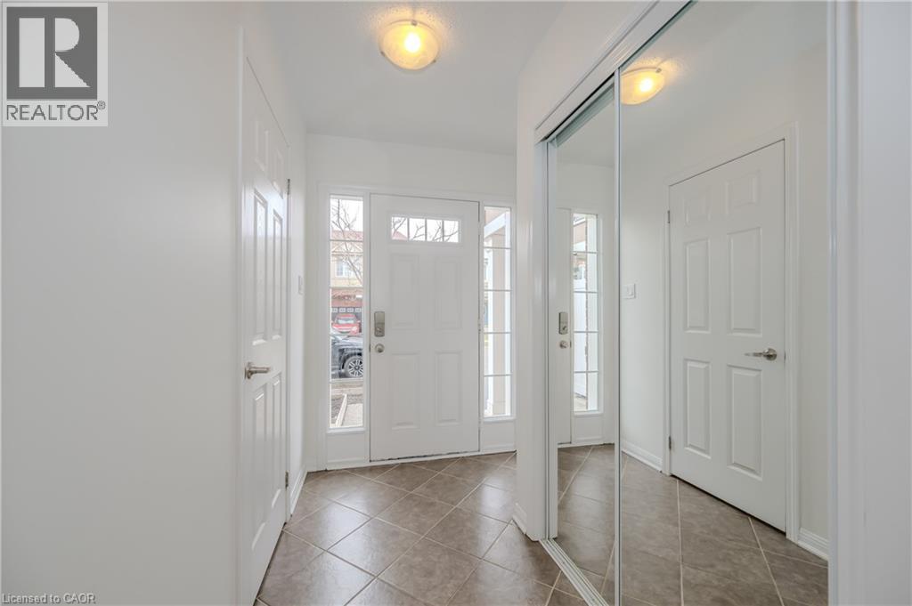 Entryway featuring a paneled front door with sidelights, transom windows, and a mirrored closet with sliding doors - 525 Cavanagh Lane, Milton, ON - Indoor Photo Showing Other Room