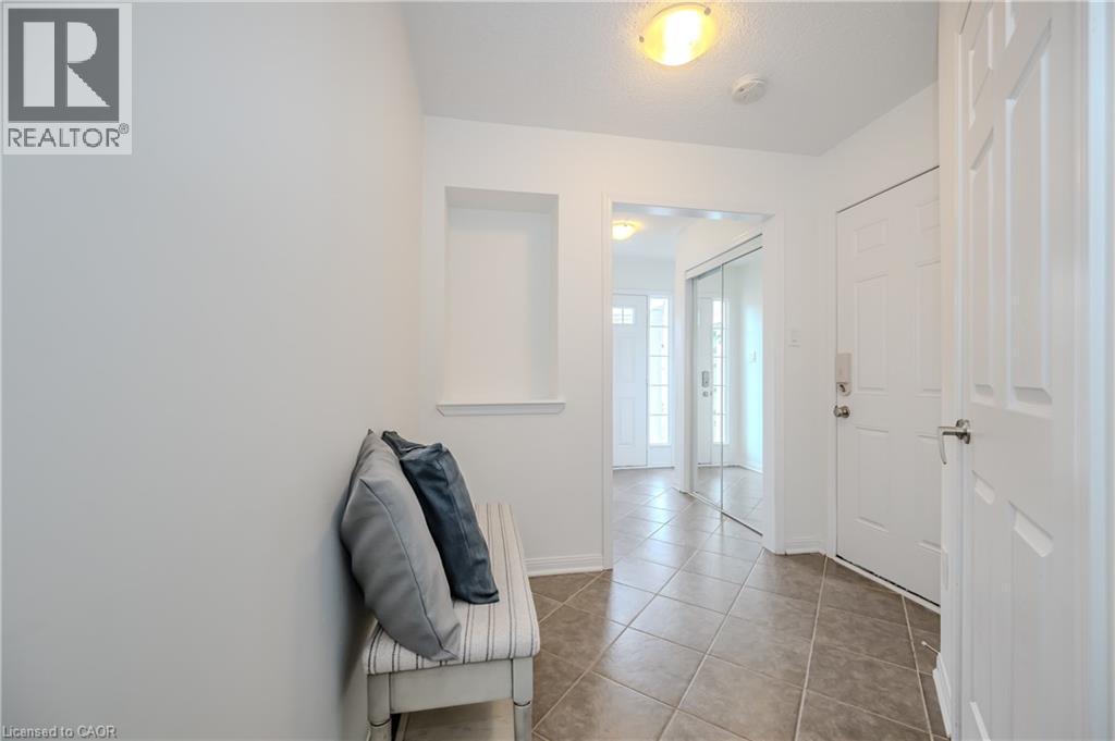 Foyer entry featuring ceramic tile flooring, a built-in wall niche, white panel doors, and a mirrored closet - 525 Cavanagh Lane, Milton, ON - Indoor Photo Showing Other Room