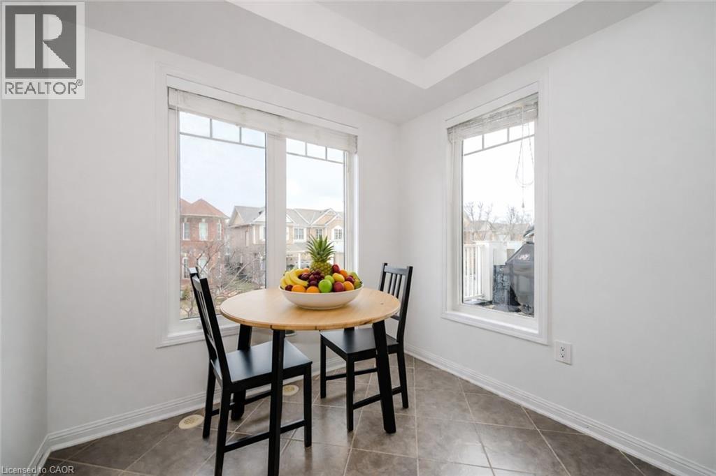 Bright dining area featuring a large window with white trim, tray ceiling, and neutral tiled flooring - 525 Cavanagh Lane, Milton, ON - Indoor Photo Showing Dining Room