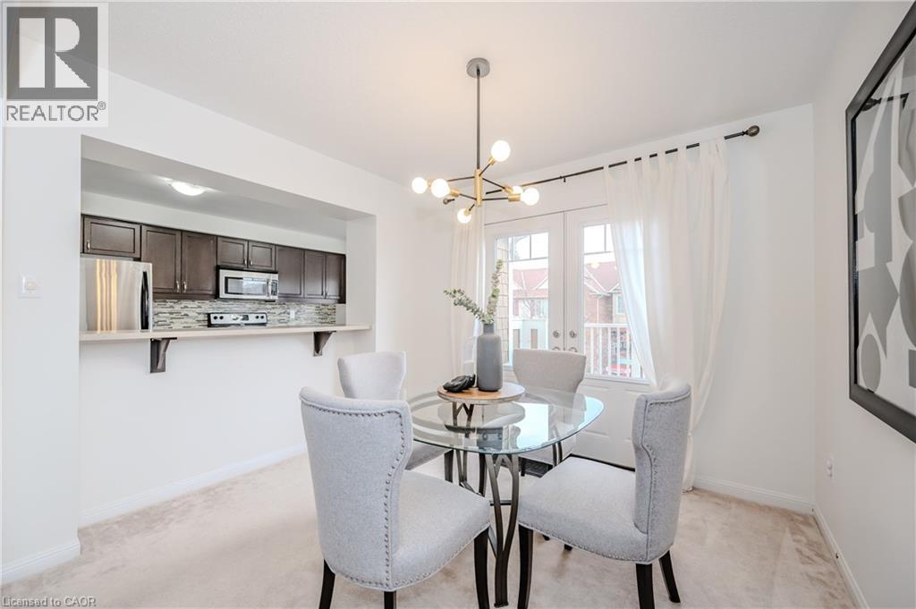 Dining area featuring a contemporary chandelier, light carpeting, and a glass-top table - 525 Cavanagh Lane, Milton, ON - Indoor Photo Showing Dining Room