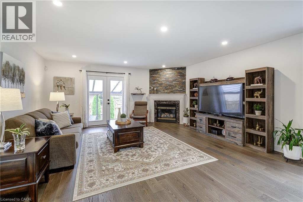Spacious living area featuring wide plank wood-finish flooring, recessed lighting, and white walls - 29 Wiltshire Place, Ancaster, ON - Indoor Photo Showing Living Room With Fireplace