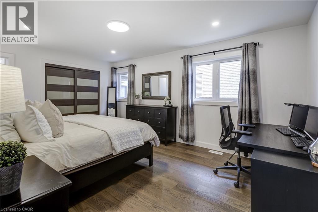 Spacious room featuring wood-finish flooring, white walls, and a large window - 29 Wiltshire Place, Ancaster, ON - Indoor Photo Showing Bedroom