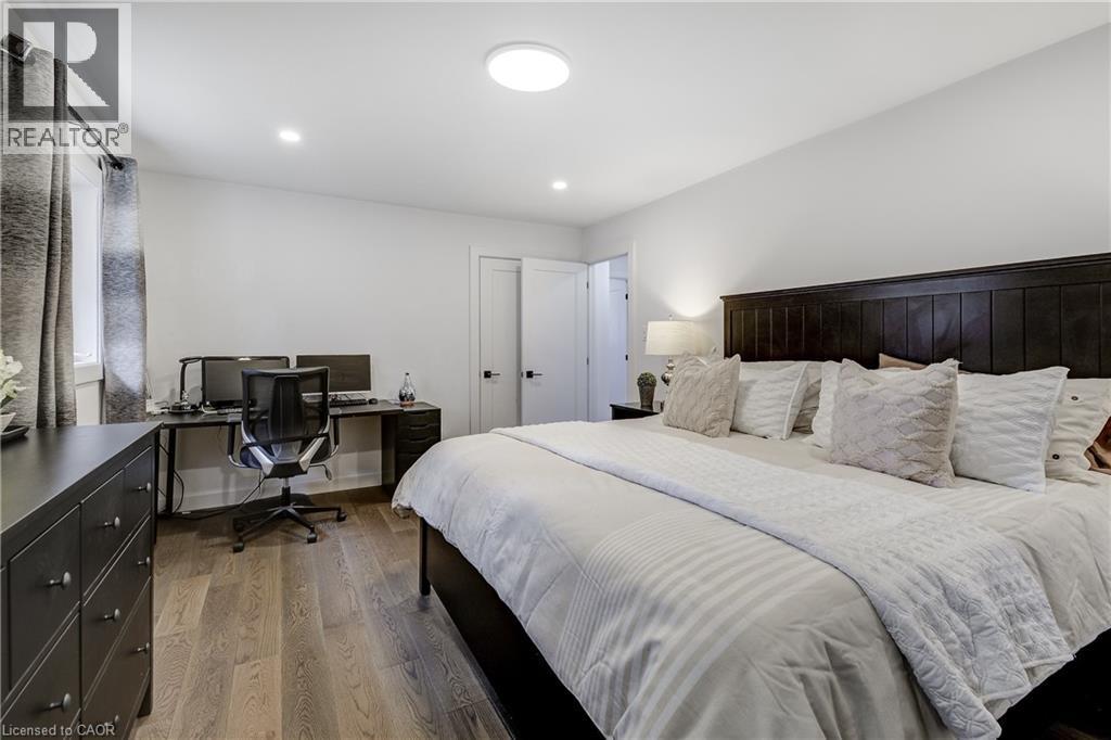 Spacious interior featuring wood-finish flooring, recessed lighting, and a dark wood paneled headboard - 29 Wiltshire Place, Ancaster, ON - Indoor Photo Showing Bedroom