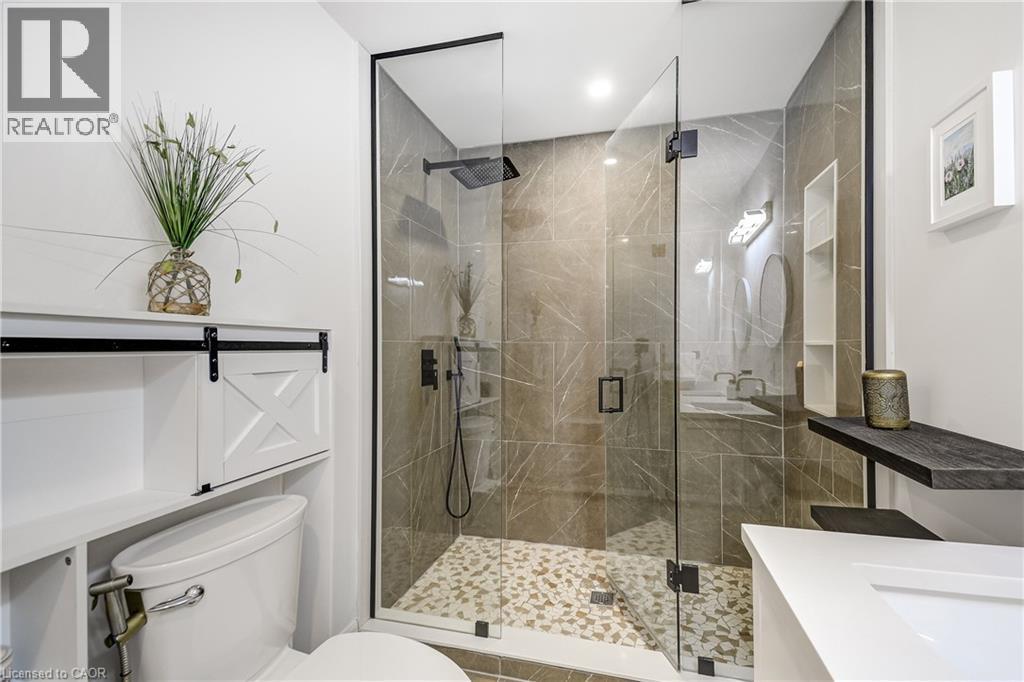 Glass-enclosed shower with large format tile surround and pebble tile flooring - 29 Wiltshire Place, Ancaster, ON - Indoor Photo Showing Bathroom