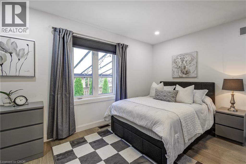 Bedroom featuring a large window with roller shades and full-length curtains, recessed lighting, and wood-finish flooring - 29 Wiltshire Place, Ancaster, ON - Indoor Photo Showing Bedroom