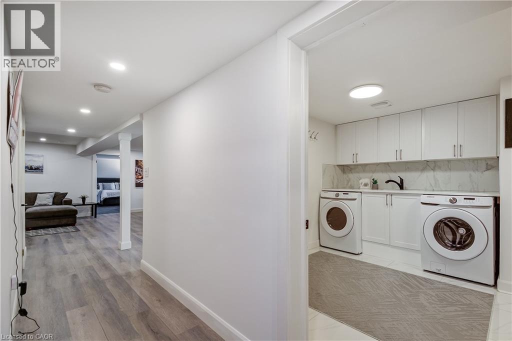 Dedicated laundry area featuring white cabinetry, a countertop, and a tiled backsplash - 29 Wiltshire Place, Ancaster, ON - Indoor Photo Showing Laundry Room