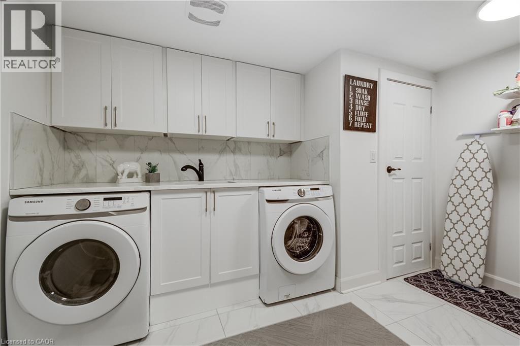 Dedicated laundry area featuring white shaker-style cabinetry, a white countertop, and a white tile backsplash - 29 Wiltshire Place, Ancaster, ON - Indoor Photo Showing Laundry Room