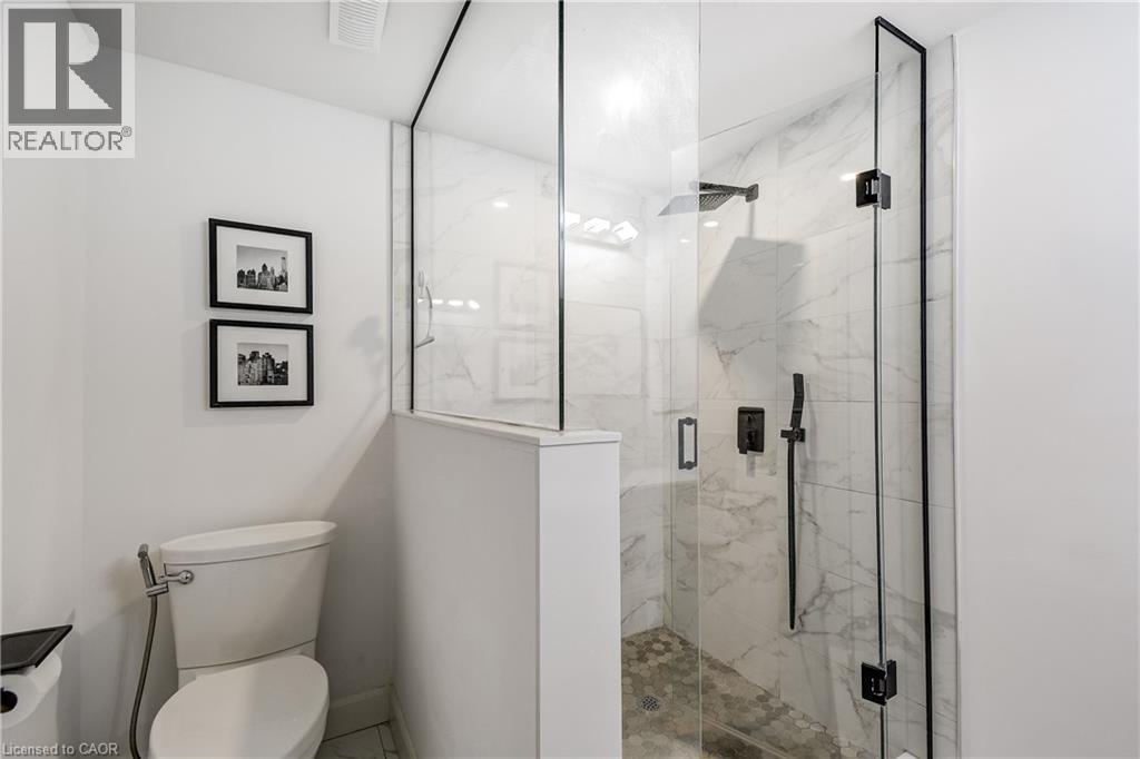 Glass-enclosed shower featuring a rain shower head, hand-held spray, and black matte fixtures - 29 Wiltshire Place, Ancaster, ON - Indoor Photo Showing Bathroom