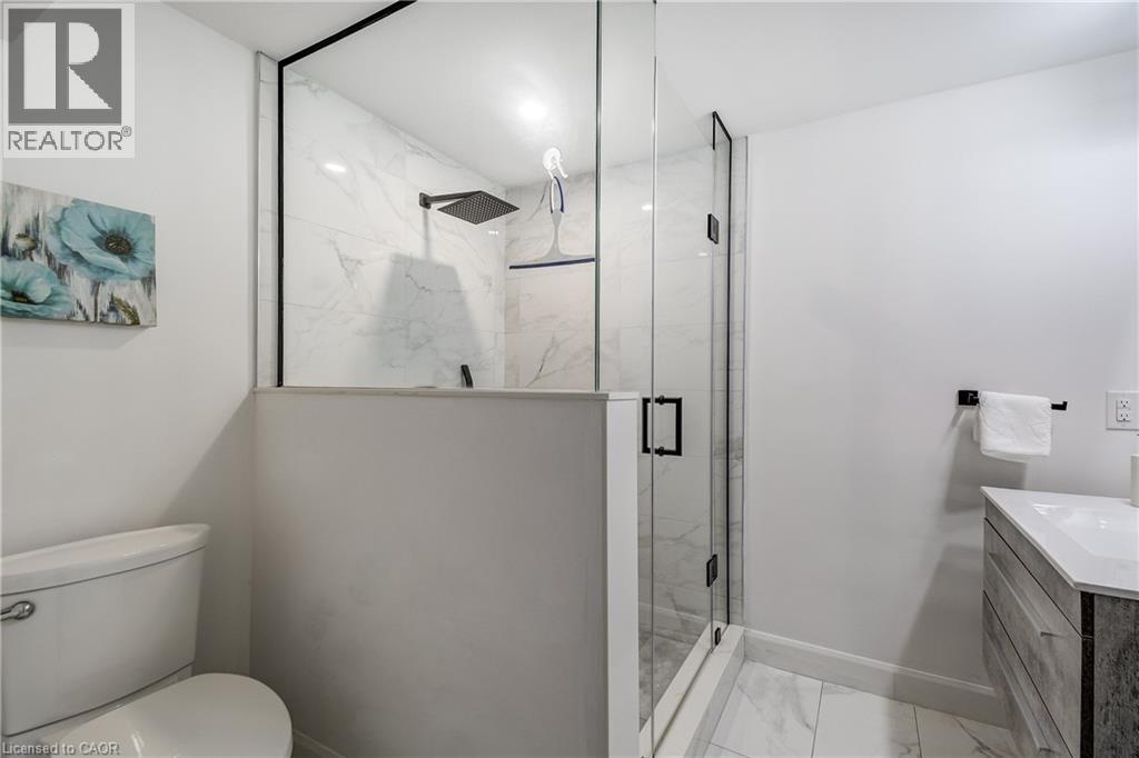 Modern bathroom featuring a glass-enclosed shower with black trim, a square matte black showerhead, and a half-wall partition - 29 Wiltshire Place, Ancaster, ON - Indoor Photo Showing Bathroom