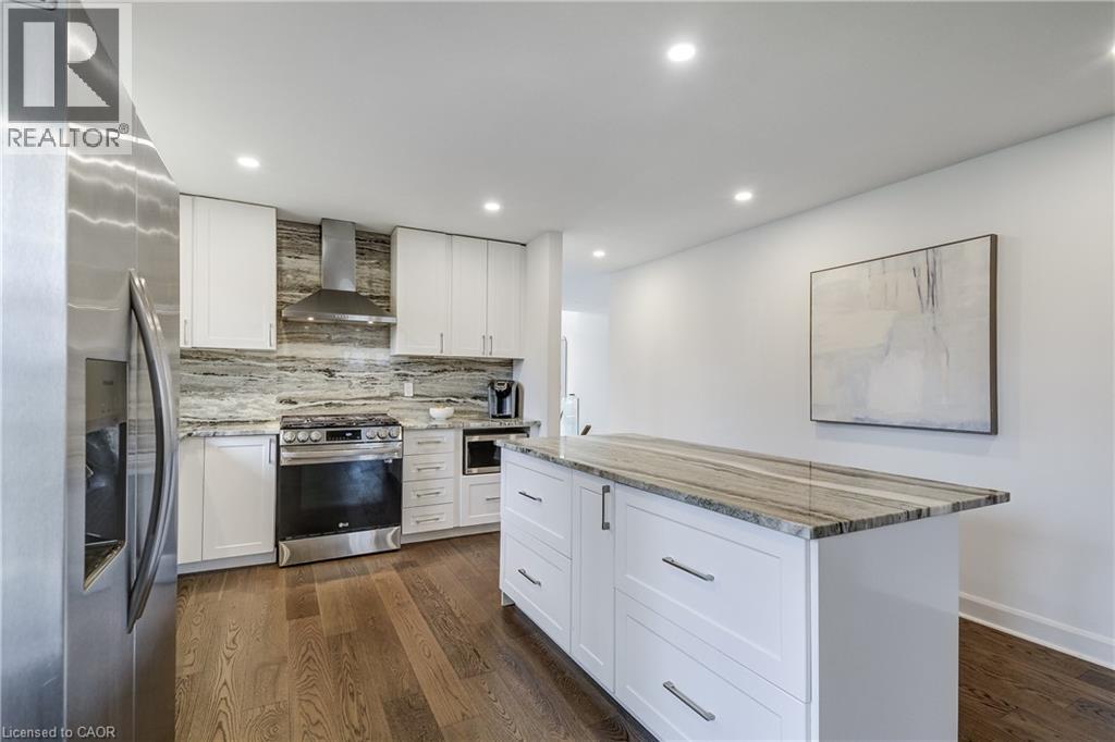 Modern kitchen featuring white cabinetry and dark wood-finish flooring - 29 Wiltshire Place, Ancaster, ON - Indoor Photo Showing Kitchen With Upgraded Kitchen