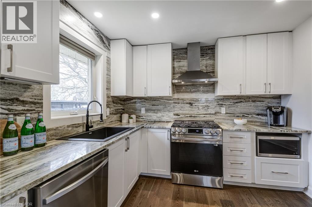 Modern kitchen featuring white shaker cabinetry, patterned stone countertops, stainless steel appliances, and wood-finish flooring - 29 Wiltshire Place, Ancaster, ON - Indoor Photo Showing Kitchen With Upgraded Kitchen
