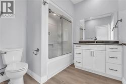 Bathroom featuring a white vanity with ample storage, dark countertop, and a large wall-mounted mirror -