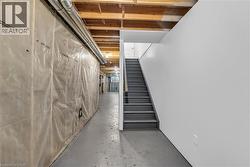 Unfinished basement area featuring exposed ceiling joists, concrete flooring, and a straight staircase with gray treads -