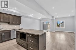 Open-concept living space featuring a kitchen with dark cabinetry, an island with a stone-finish countertop, and a mosaic tile backsplash -