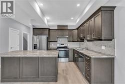 Kitchen featuring dark wood-finish cabinetry, stainless steel appliances, a light-toned countertop, and a mosaic tile backsplash -