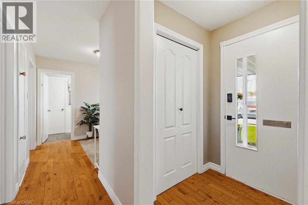 Entryway featuring wood-finish flooring, a white paneled entry door with vertical glass inserts, and a bi-fold closet door - 120 Elgin Crescent, Waterloo, ON - Indoor Photo Showing Other Room