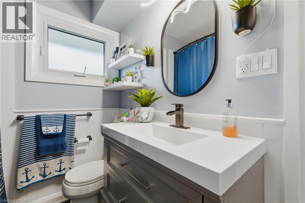 Bathroom featuring a contemporary vanity with an integrated sink, dark bronze-finish faucet, and an oval-framed mirror - 120 Elgin Crescent, Waterloo, ON - Indoor Photo Showing Bathroom
